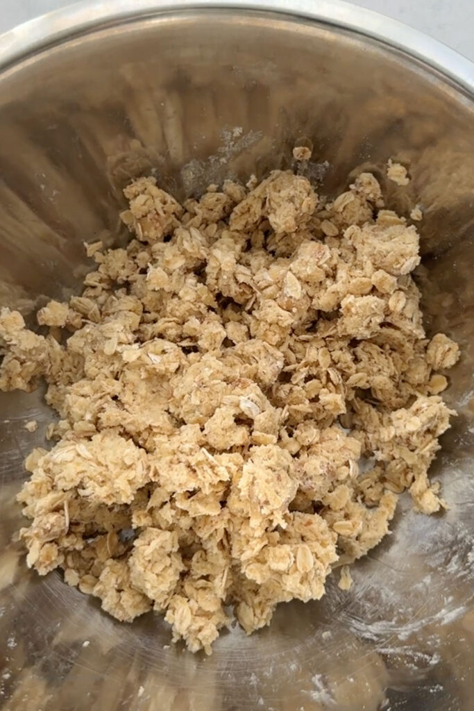 step 1 instruction on making vegan cheesecake pie crumble with all purpose flour, vegan butter, sugar, walnuts, and rolled oats