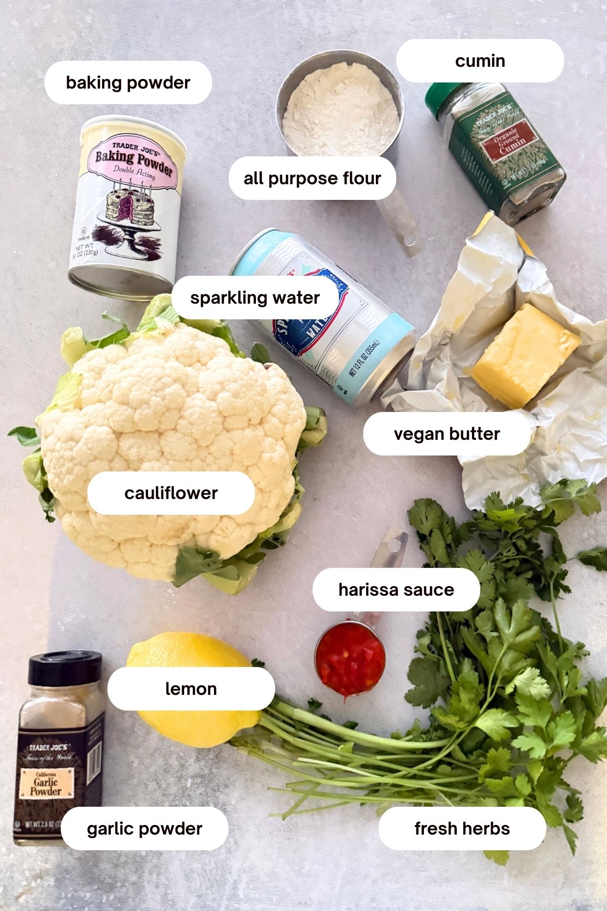 roasted harissa cauliflower bites ingredients: baking powder, seltzer water, cauliflower, garlic powder, all purpose flour, vegan butter, harissa, fresh herbs, cumin